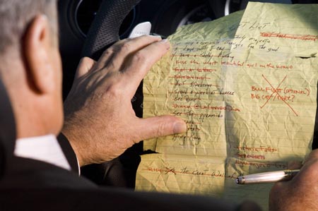 Links im Bild ein Fahrer, eine geknickte, handgeschriebene Liste liegt auf dem Lenkrad, die rechte Hand hlt eine silbernen Stift.